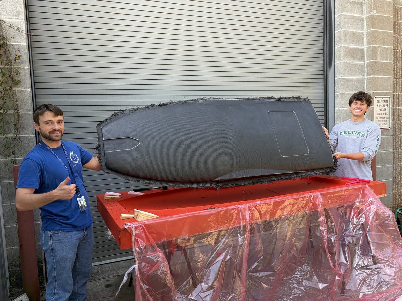 The finished full-length carbon bottom skin beside the mold it was built on