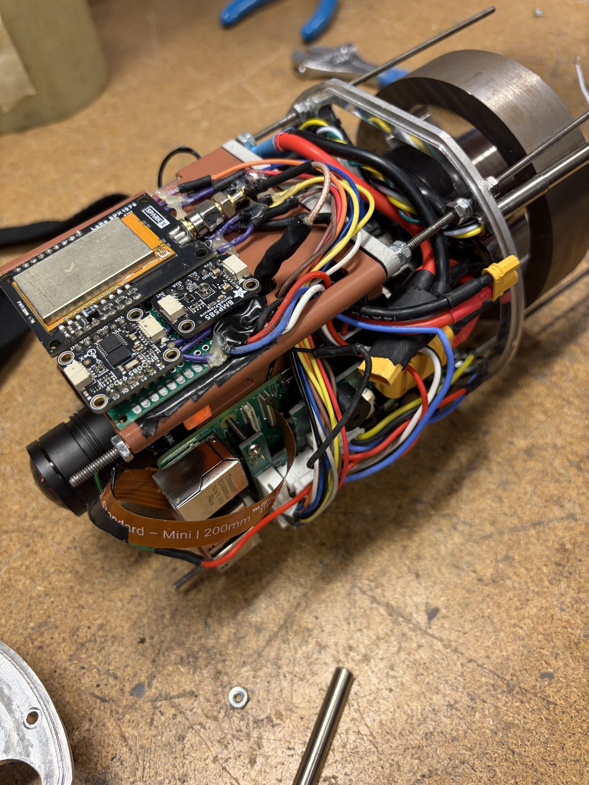 The assembled ATLAS payload on a workbench, showing the avionics stack, wiring harness, camera and machined bulkhead rings